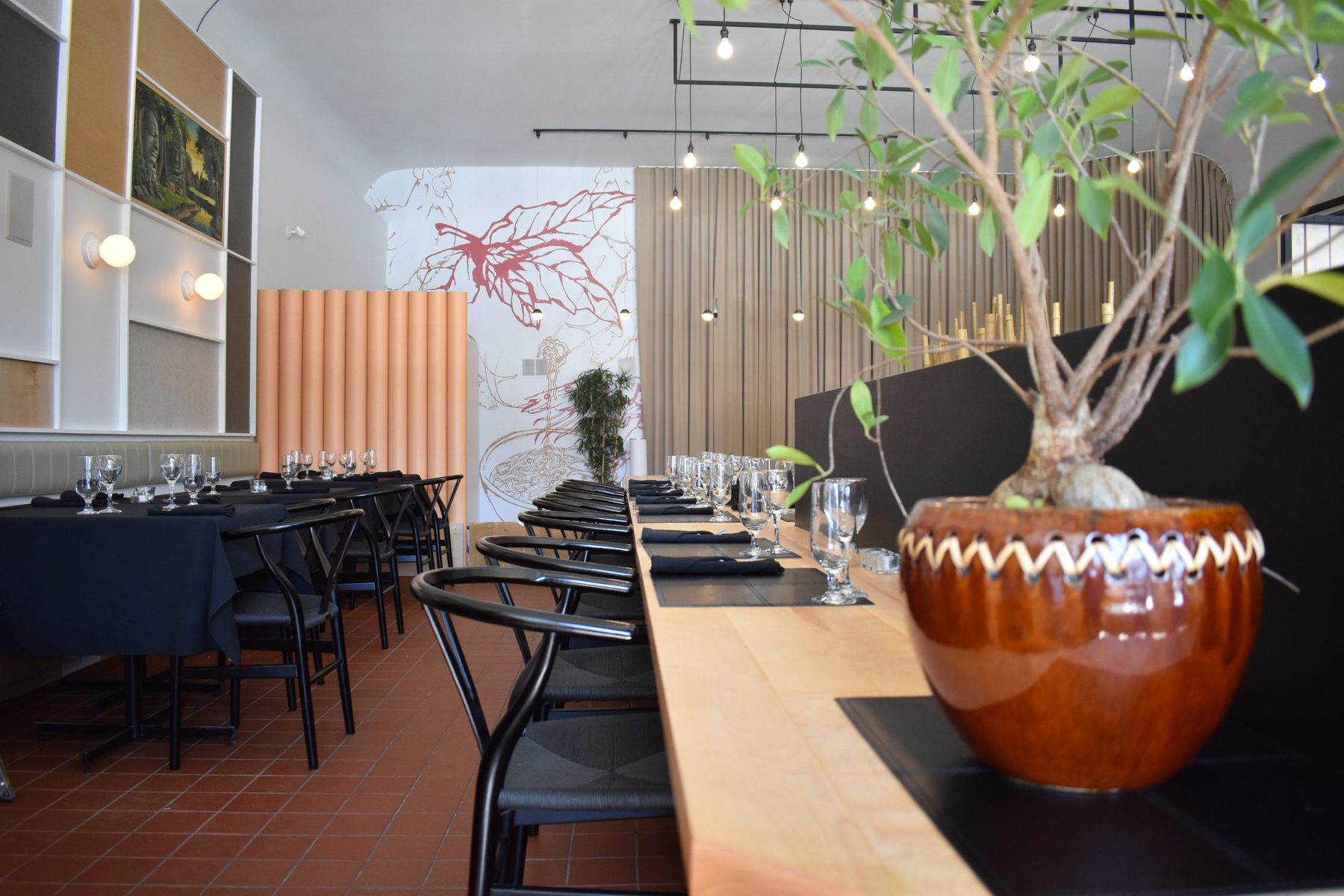 La salle à manger, ses tables dressées et son grand bonsaï